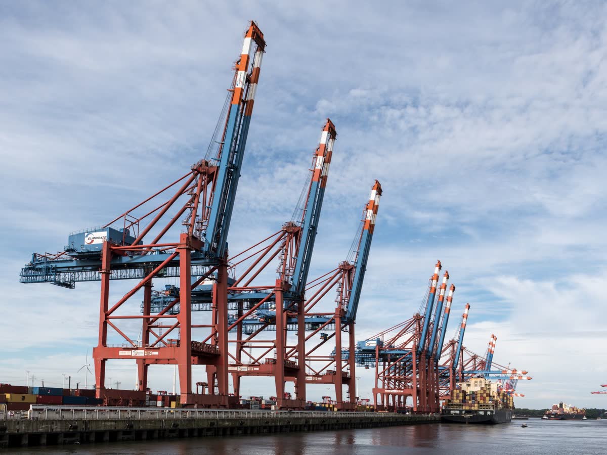 Ship-to-shore container cranes at a port under a cloudy sky